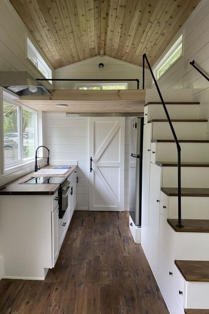 the interior of a tiny house with stairs leading up to it's kitchen area