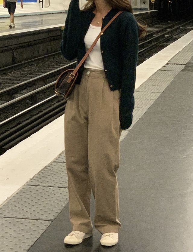 a woman is standing on the platform talking on her cell phone