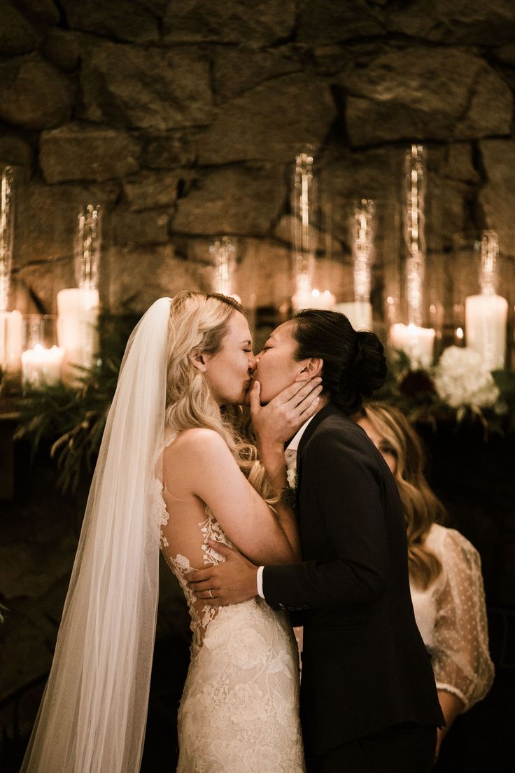 a bride and groom kissing in front of candles