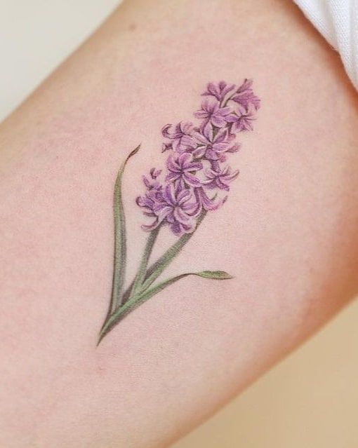 a close up of a person's thigh with a tattoo on it that has purple flowers