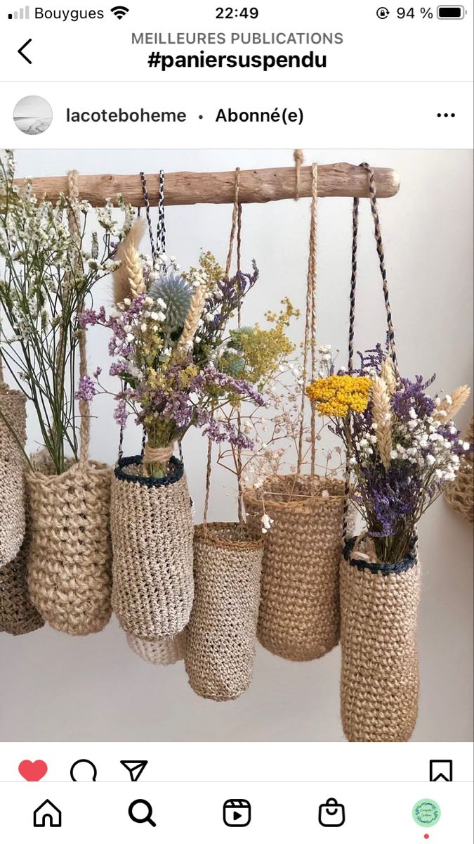 several vases filled with different types of flowers hanging from a wooden beam in front of a white wall