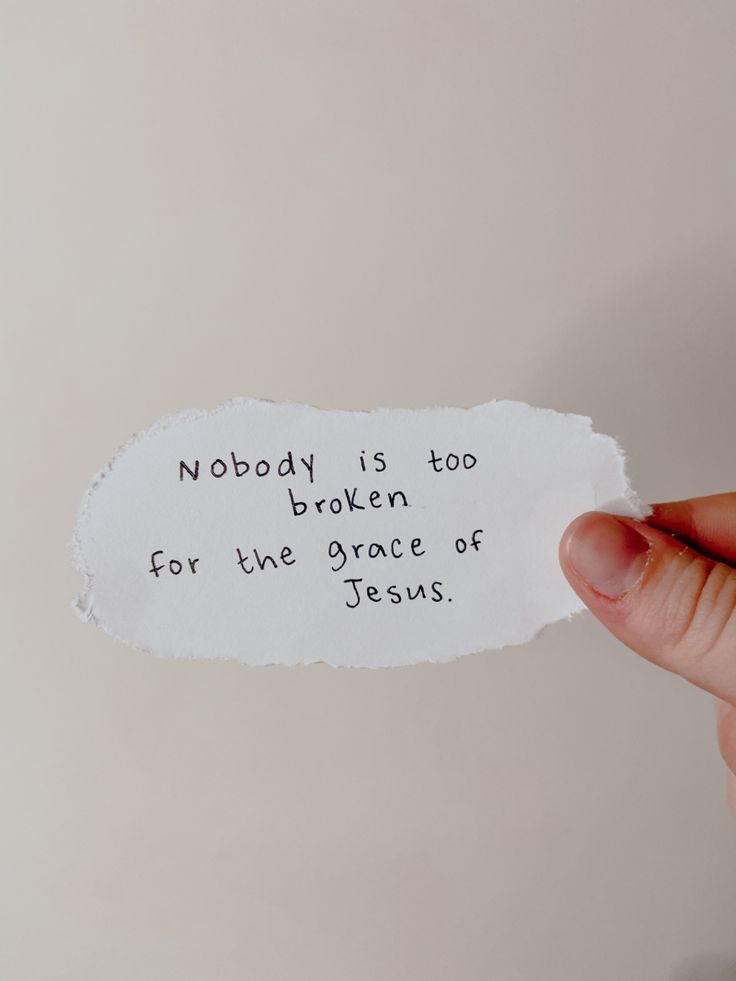 someone holding up a piece of paper that says nobody is too broken for the grace of jesus