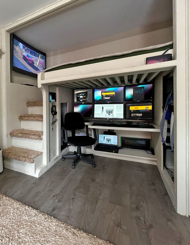 a living room with stairs and tvs on the wall