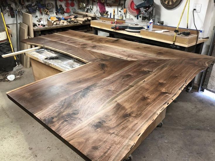 a large wooden table sitting inside of a garage next to other workbench and tools