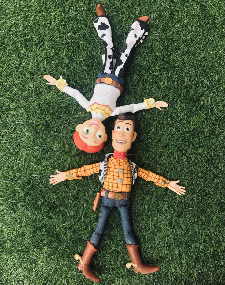 an overhead view of two toy figures laying on the grass with their heads in the air