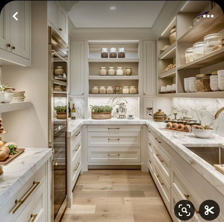 a kitchen filled with lots of white cabinets and counter top space next to a wooden floor