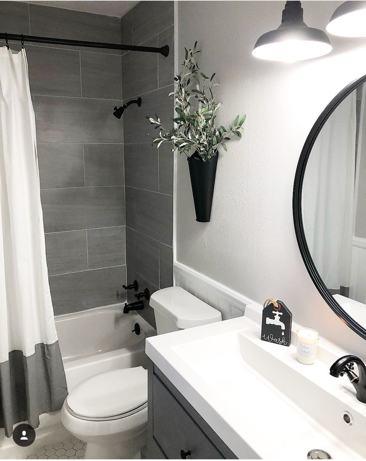 a white toilet sitting next to a bath tub in a bathroom under a mirror with lights on it