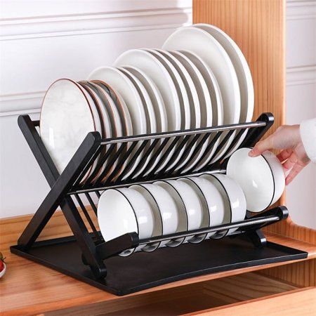 a stack of plates sitting on top of a black rack next to a wooden table