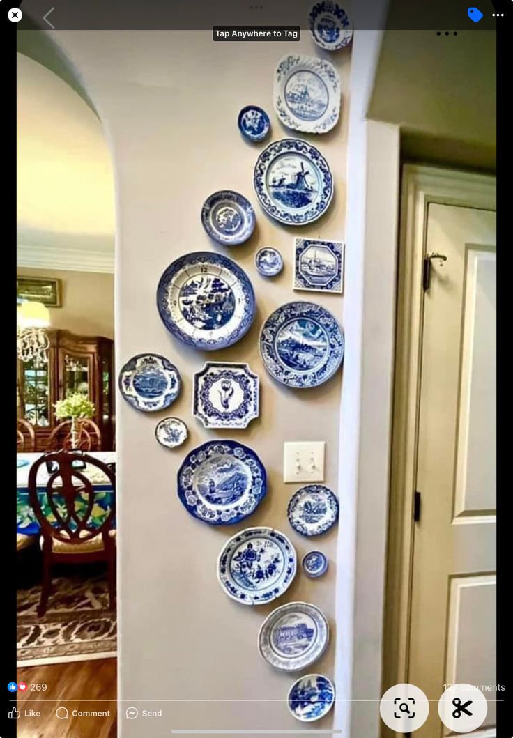 a bunch of blue and white plates hanging on the wall next to a dining room table