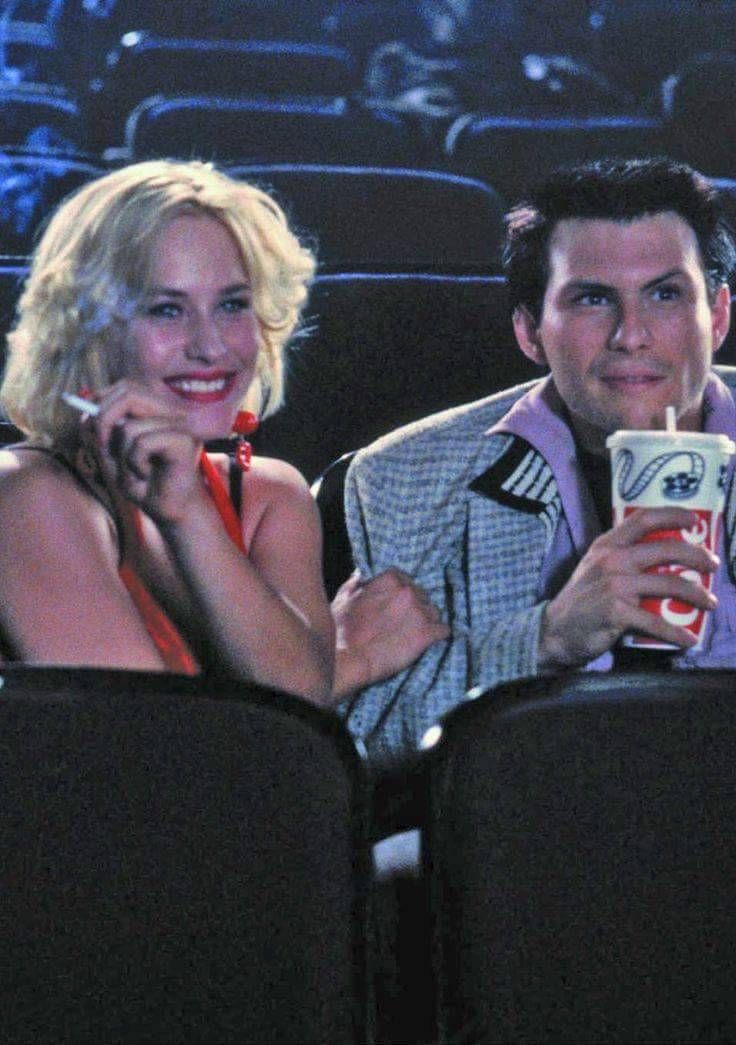 a man and woman sitting next to each other in front of an empty theater seat