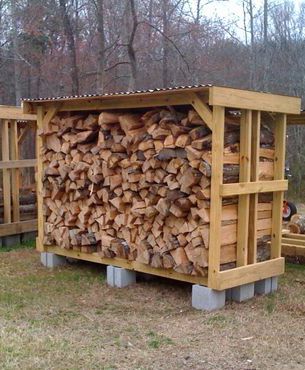 a large pile of wood sitting in the middle of a field next to some trees