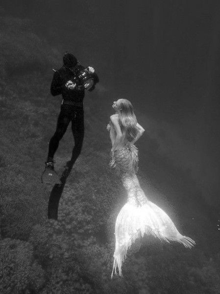 two people are diving in the water and one person is holding a camera behind them