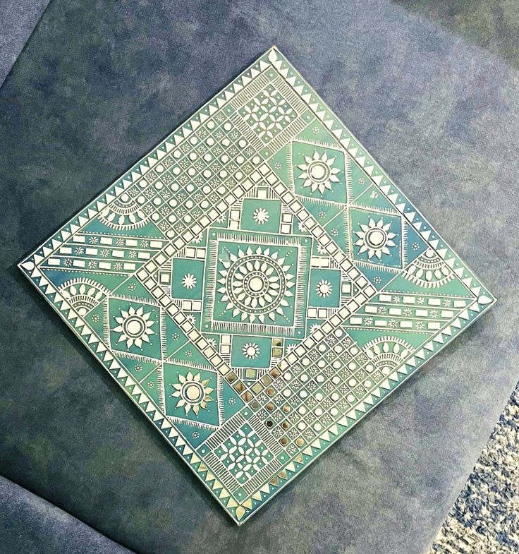 a green and white tile on the ground with an intricate design in the top corner