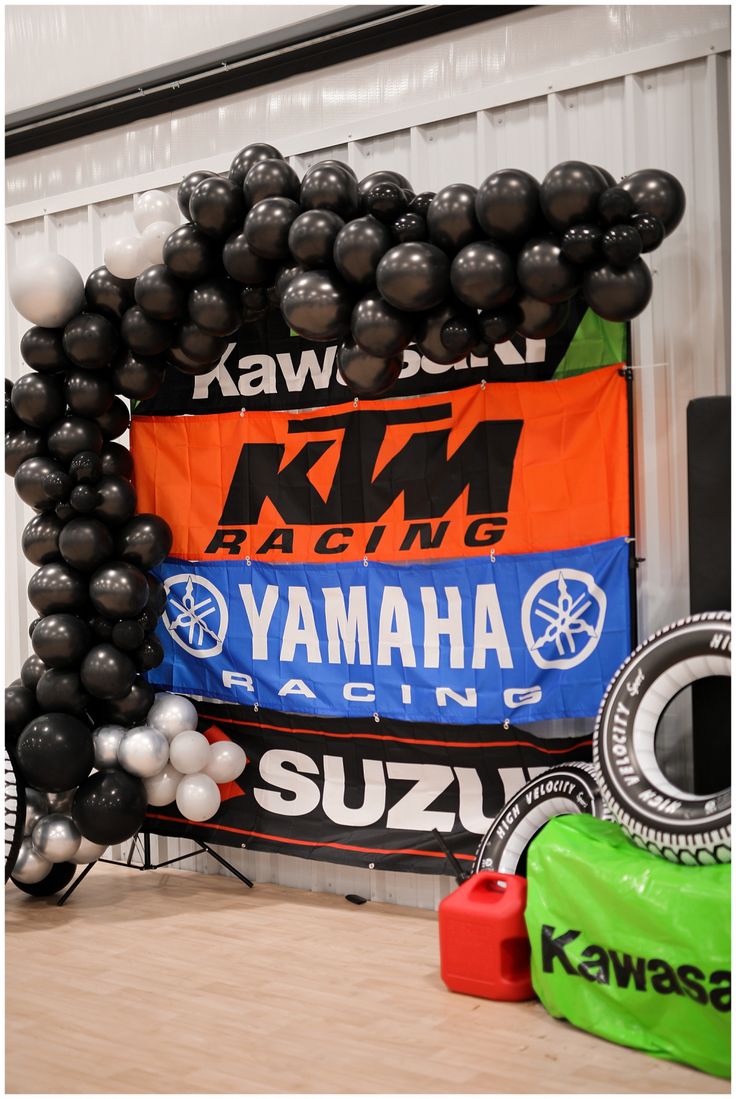 an assortment of black and white balloons in front of a sign that reads km racing yamaha racing suzuki