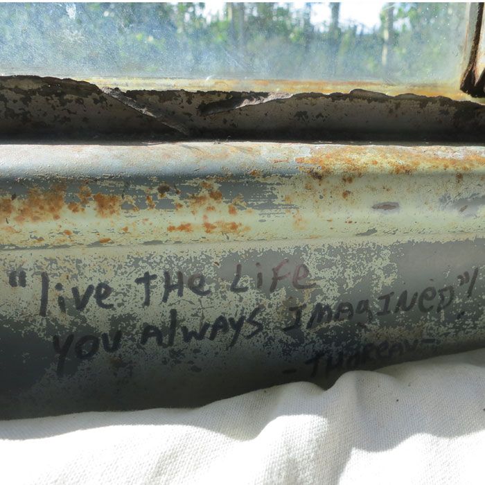 an old pipe with writing on it sitting next to a window sill in the sun