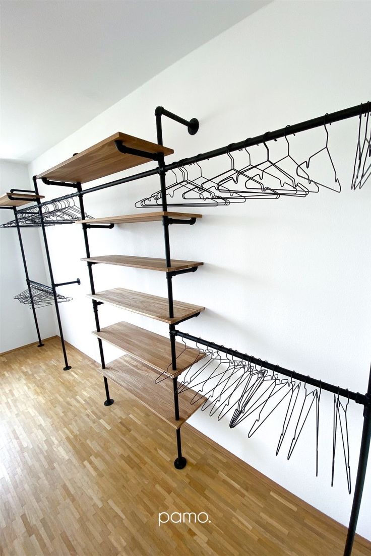 an empty room with some shelves and clothes racks on the wall in front of it