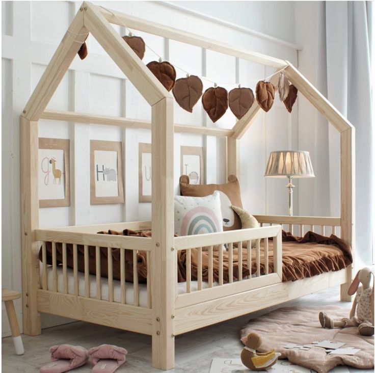 a child's bed with a wooden frame and canopy over it, sitting on the floor