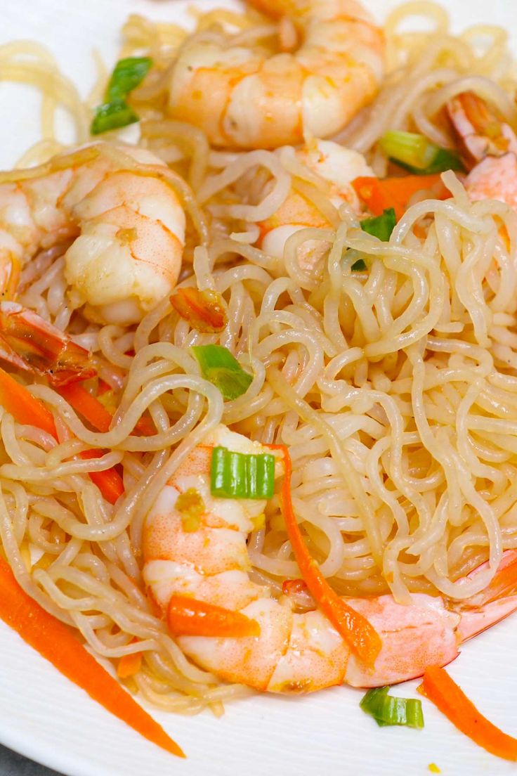 a plate with noodles, shrimp and carrots on it