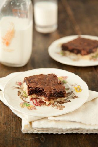 two plates with brownies on them sitting on a table next to a bottle of milk