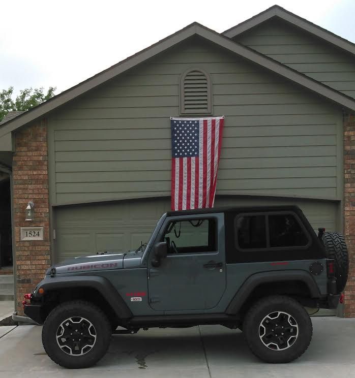 a jeep parked in front of a house with an american flag on top