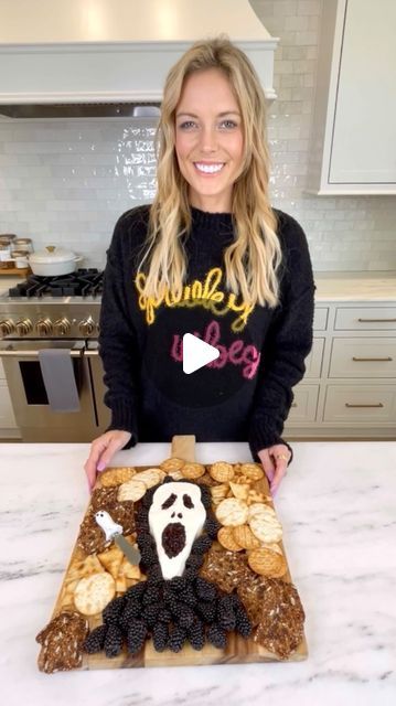 a woman standing in front of a cake with a ghost face on it and blackberries