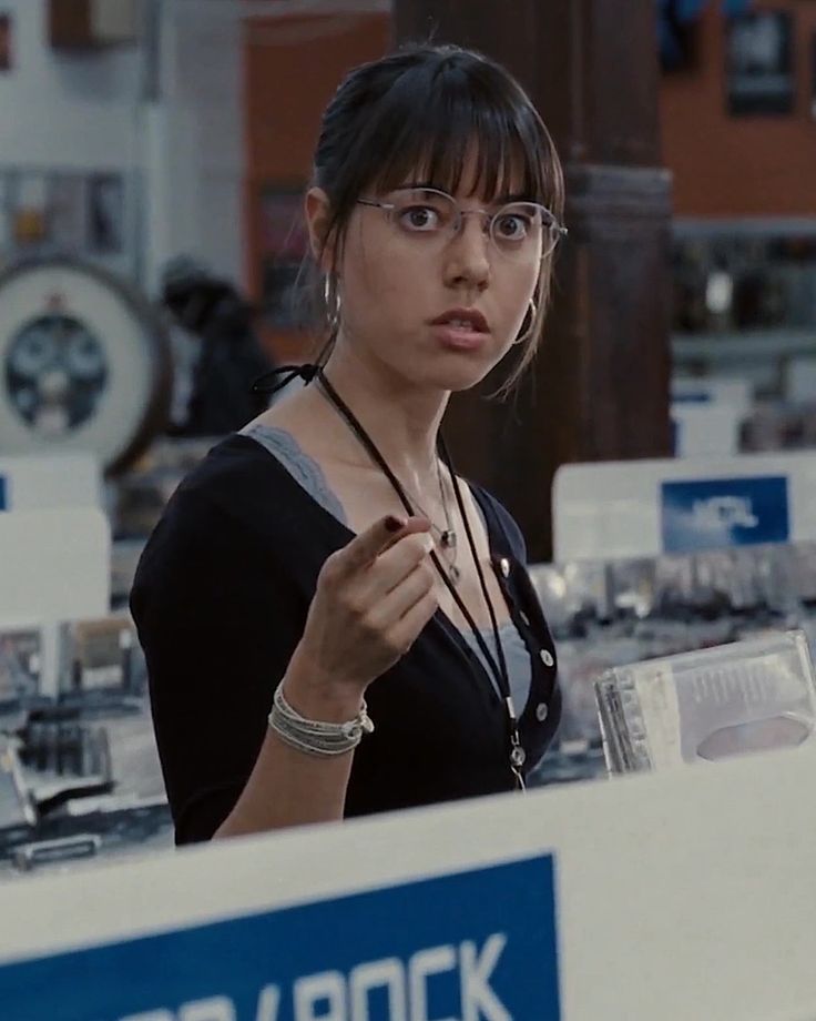 a woman wearing glasses standing in front of a display