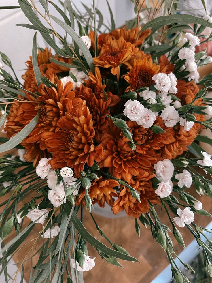 a vase filled with lots of orange and white flowers