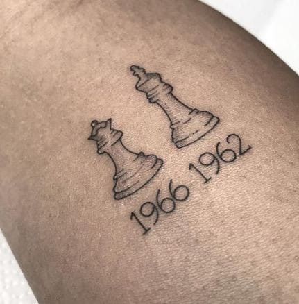 a tattoo with two chess pieces on it's thigh, and the words 1940 written in black ink