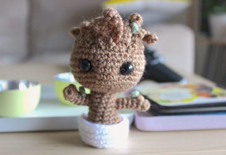 a small crocheted animal sitting on top of a table next to a book