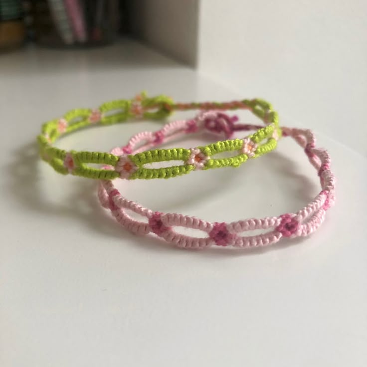 three bracelets with flowers on them sitting on top of a white table next to a bookshelf