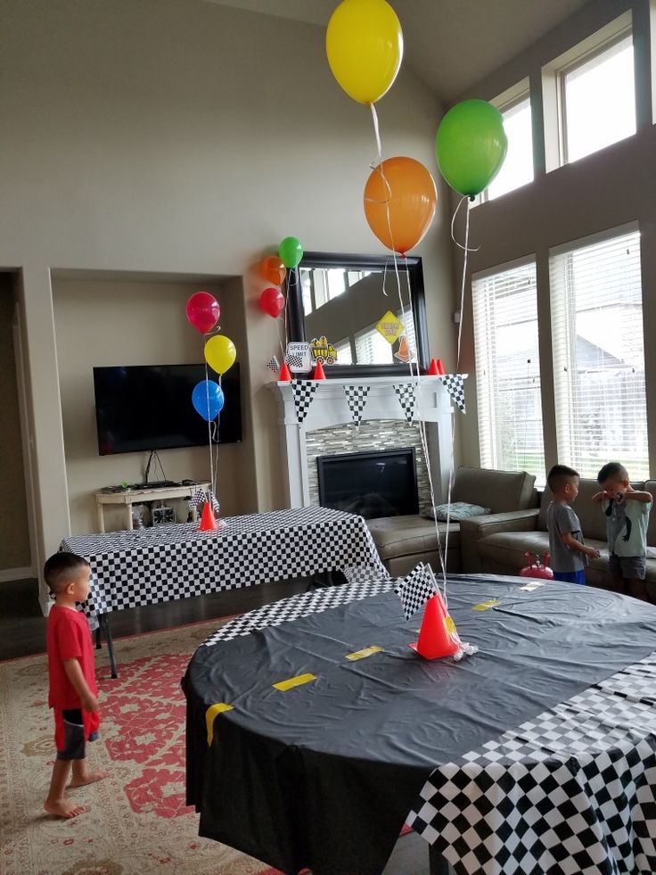 a boy standing in front of a table with balloons on it