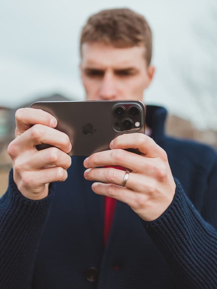 a man in a blue jacket is looking at his cell phone