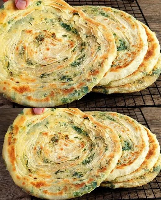 four flat breads with spinach and cheese in the middle on a cooling rack