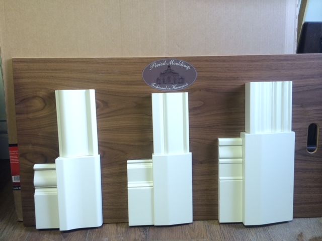 three white vases sitting next to each other on a wooden shelf in front of a cardboard box