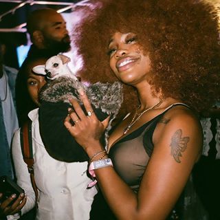 a woman with an afro holding a small animal