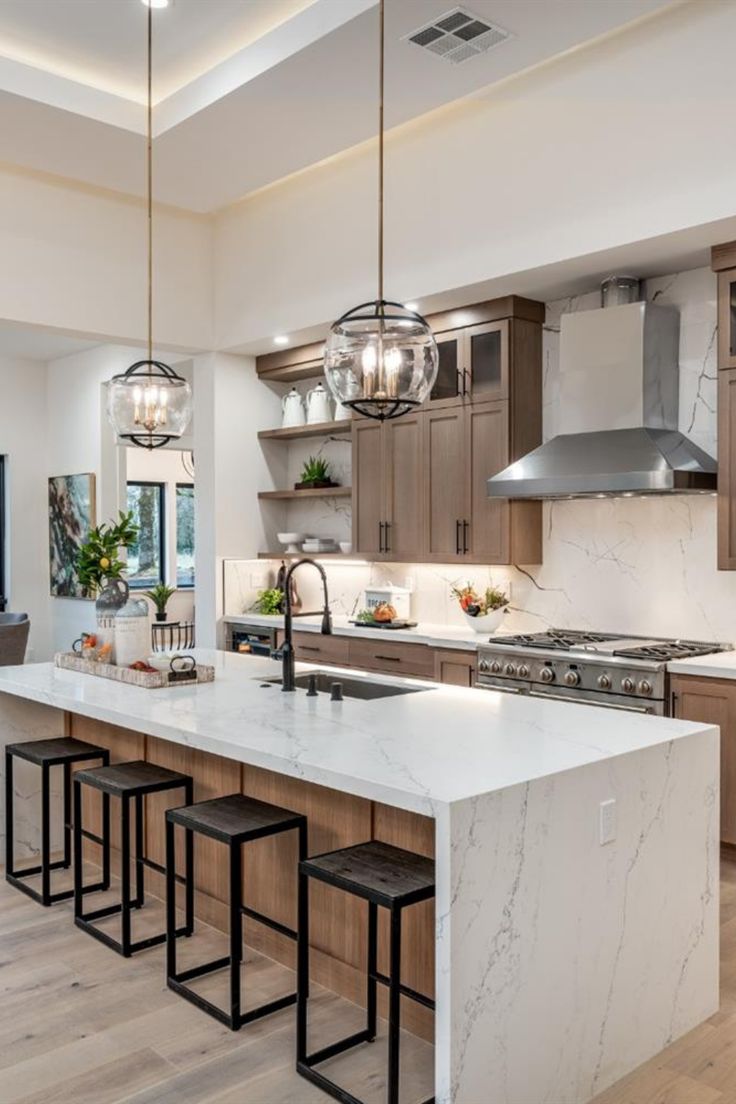 a large kitchen with marble counter tops and wooden flooring, along with pendant lights hanging from the ceiling