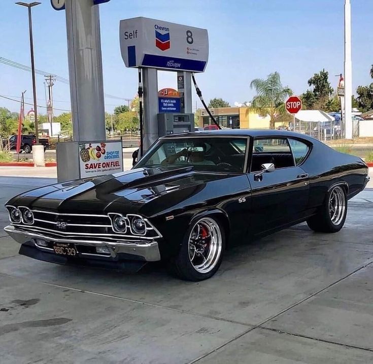 an old muscle car parked at a gas station