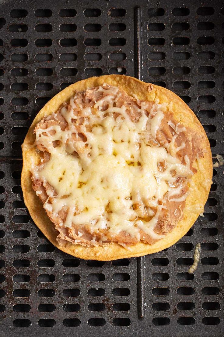 a pizza sitting on top of a grill covered in cheese