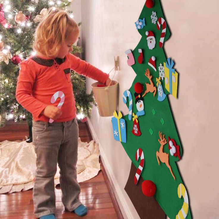 a little boy standing in front of a christmas tree with decorations on the bottom half