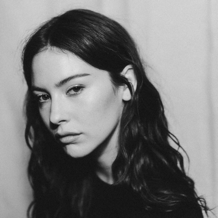 a black and white photo of a woman with long dark hair looking at the camera