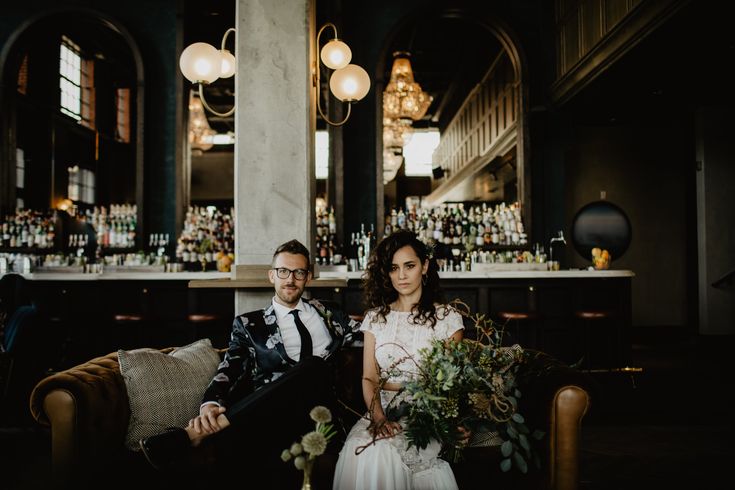 a bride and groom sitting on a couch in a bar