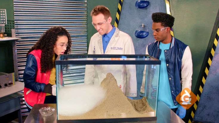 two men and a woman looking at sand in a glass case on the set of grey's anatomy