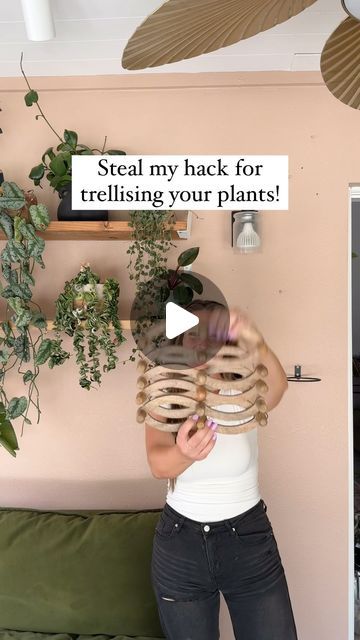 a woman standing in front of a green couch holding a plate with plants on it