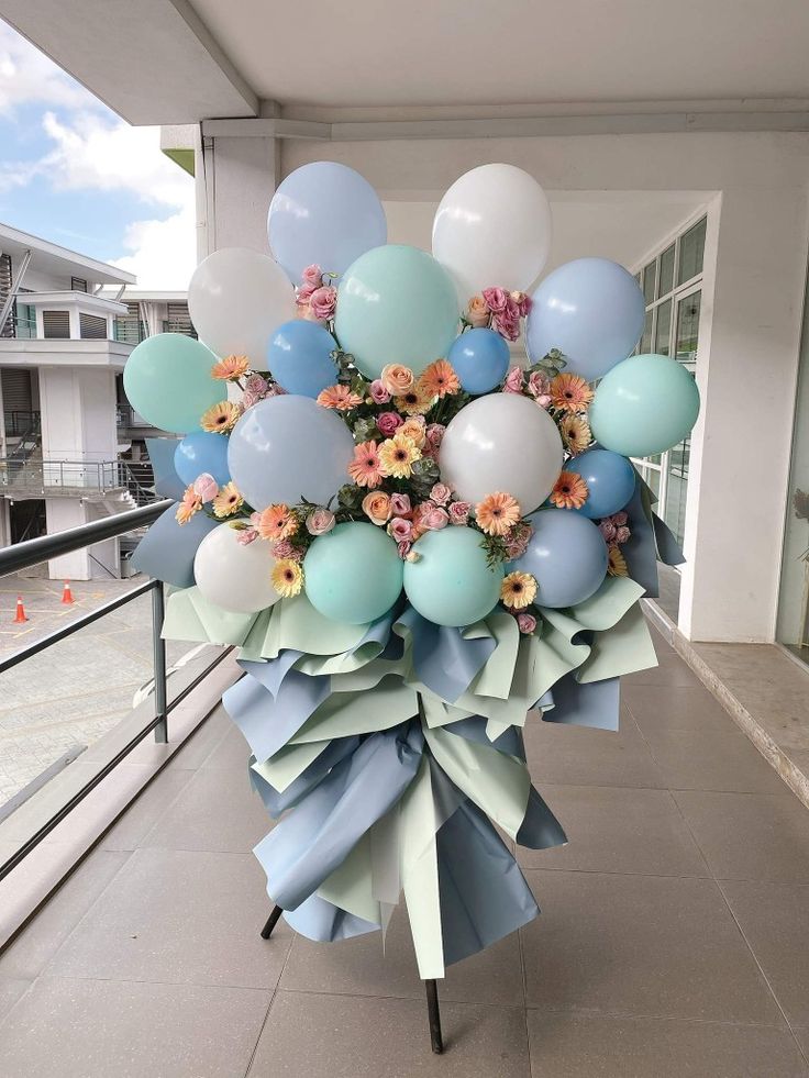 a bunch of balloons that are sitting on a stand in front of a building with flowers