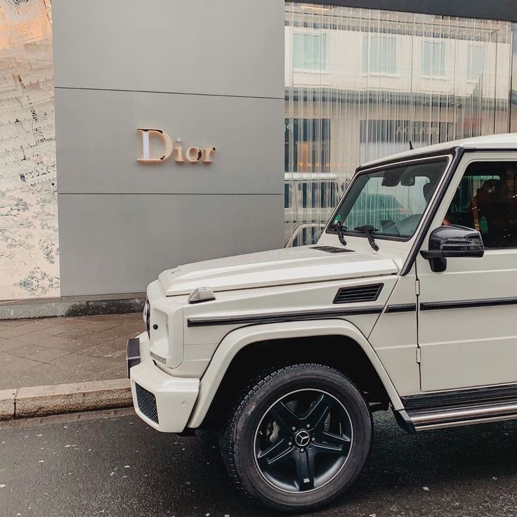 a white mercedes g - class parked in front of a building