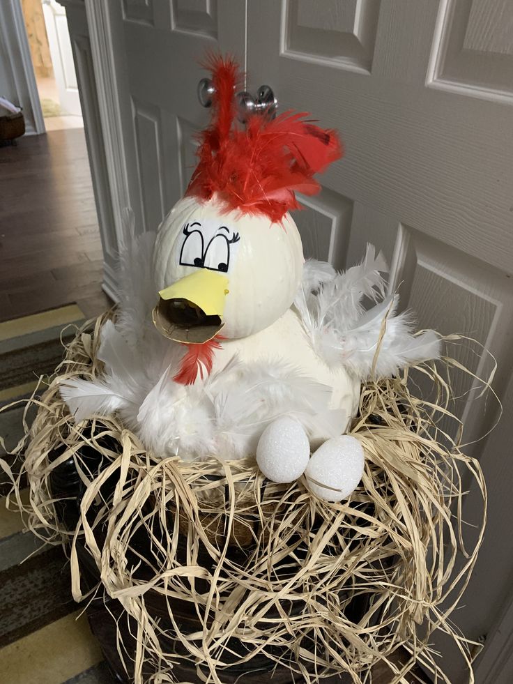 a stuffed chicken sitting on top of a nest filled with hay and eggs in front of a door