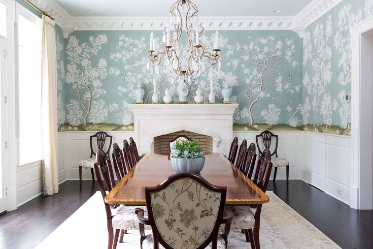 a dining room table with chairs and a chandelier hanging from the ceiling in front of a fireplace