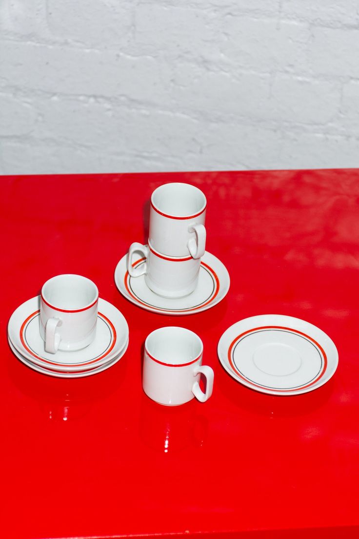 a red table topped with white plates and cups