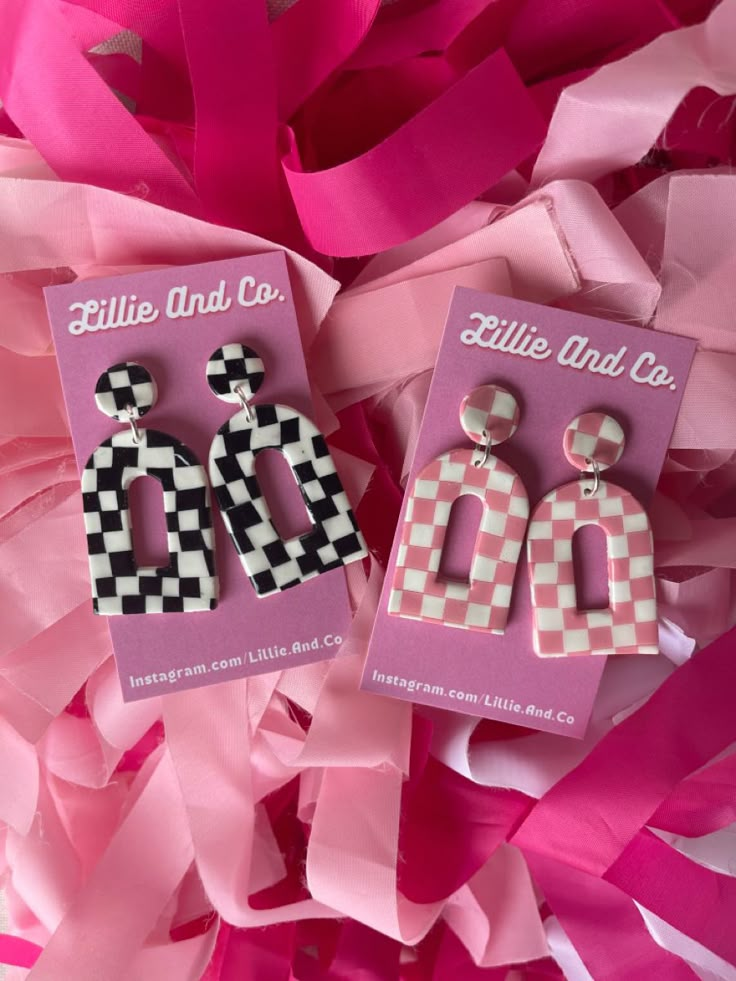 two pink and white checkered earrings are on display