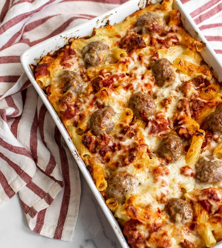 a casserole dish with meatballs and cheese in it on a red and white towel